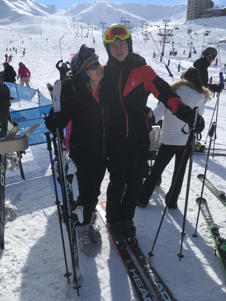 Image shows Tracey arm in arm with son Harry both dressed in ski gear with snowy mountains as backdrop.