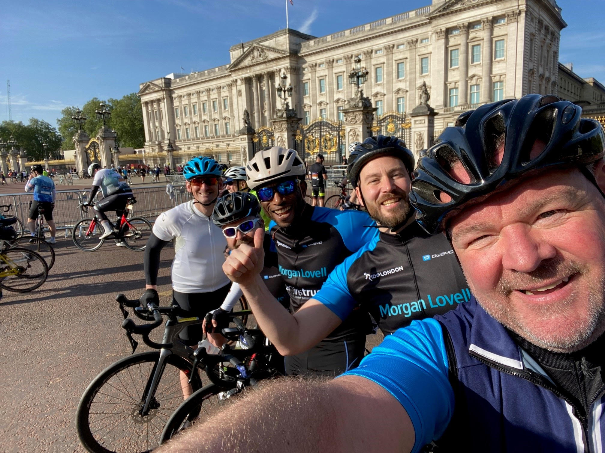 Selfie of the Morgan Lovell team on their ride for brainstrust. They are smiling in front of Buckingham palace with their bikes.